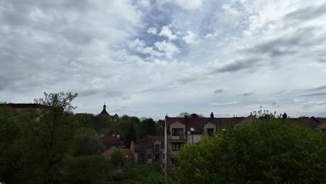 Cielo-Nublado-Sobre-Una-Ciudad-De-Tamaño-Mediano,-árboles-Verdes-Primaverales-En-El-Fondo