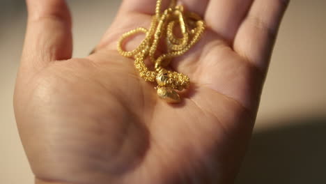 gold wedding necklace in hand