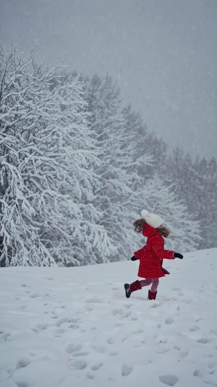 A child in a red coat joyfully runs through a snowy landscape. Captured from a low angle, the video