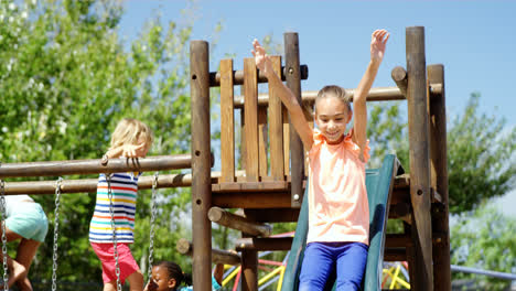 Glückliches-Schulmädchen,-Das-Auf-Der-Rutsche-Auf-Dem-Spielplatz-Spielt