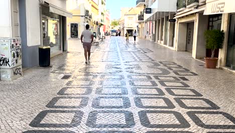 El-Hombre-Pasea-Por-El-Encantador-Centro-Adoquinado-De-Faro,-Inmerso-En-Su-Encanto-Histórico-Y-Su-Vibrante-Atmósfera.