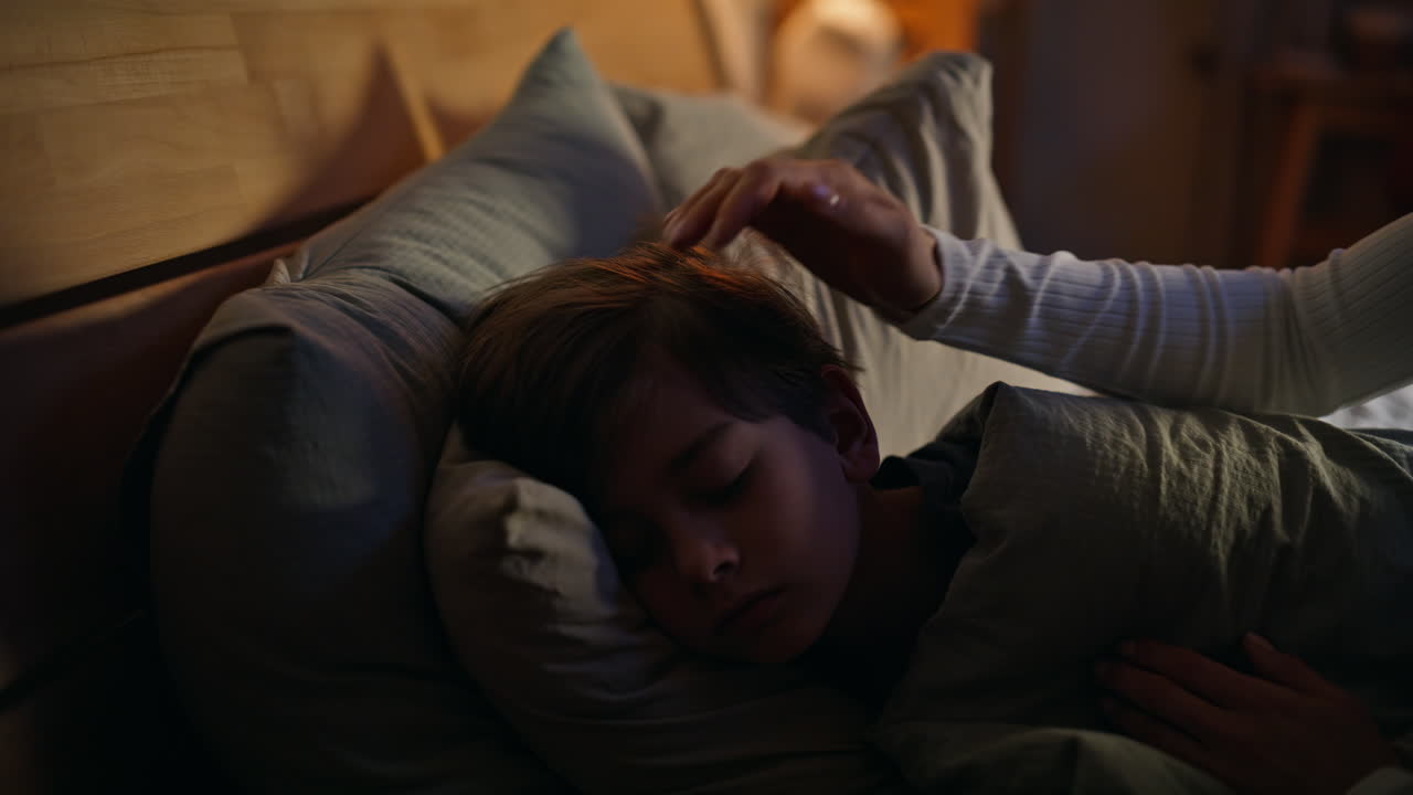 Loving mom caressing sleeping son head feeling love tenderness bedroom closeup