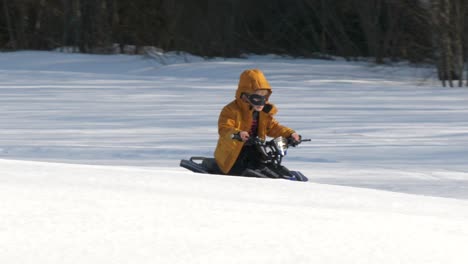 kid wearing superhero mask rides atv in snow, slow motion