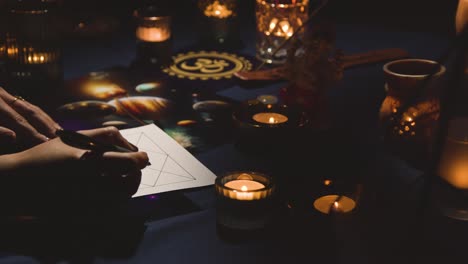 primer plano de una mujer dibujando astrología lagna o gráfico de nacimiento en la mesa 1 a la luz de las velas