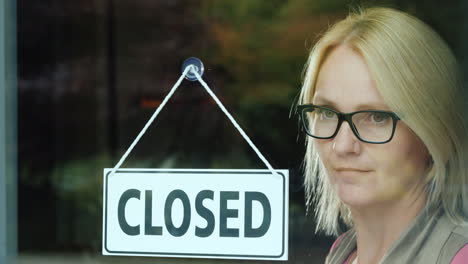 a portrait of a sad woman at the table is closed on the door going out of business concept