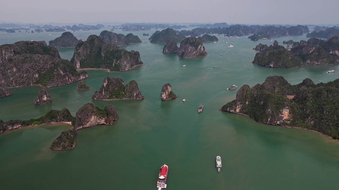 Vịnh Hạ Long Việt Nam: Cảnh quay drone bay vào các tàu du lịch và thuyền qua các đảo đá ngọc bích trên biển.