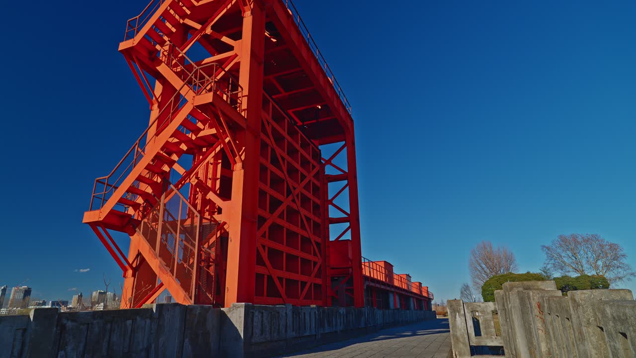 Bright Orange Industrial Floodgate Structure Against a Clear Blue Sky