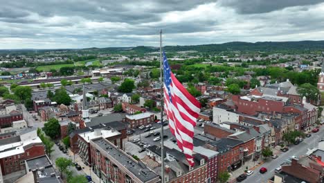 Windy-day-with-waving-American-flag-over-small-historic-town-in-USA