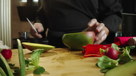 A chef cutting a mango and preparing fresh produce in a kitchen