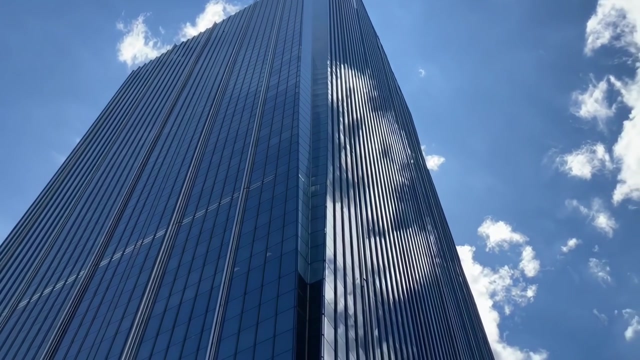 Vista de baixo ângulo de um moderno arranha-céu de vidro contra o céu azul