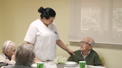 caregiver talking to senior man in canteen at nursing home