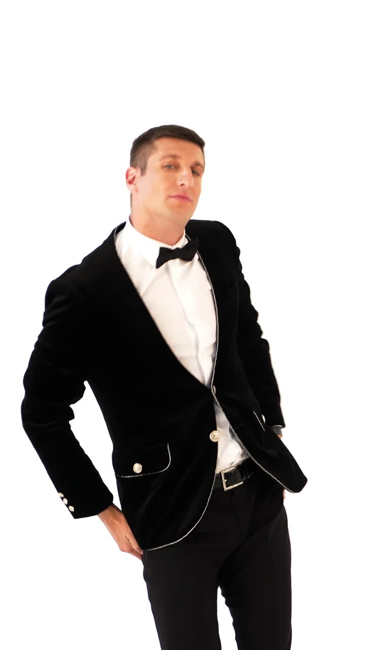 funny man in a black suit and white shirt is dancing macarena on the background of white studio. Parody of the popular dance. Macarena Vertical video