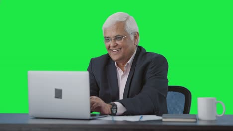 Happy-senior-Indian-manager-working-on-laptop-Green-screen