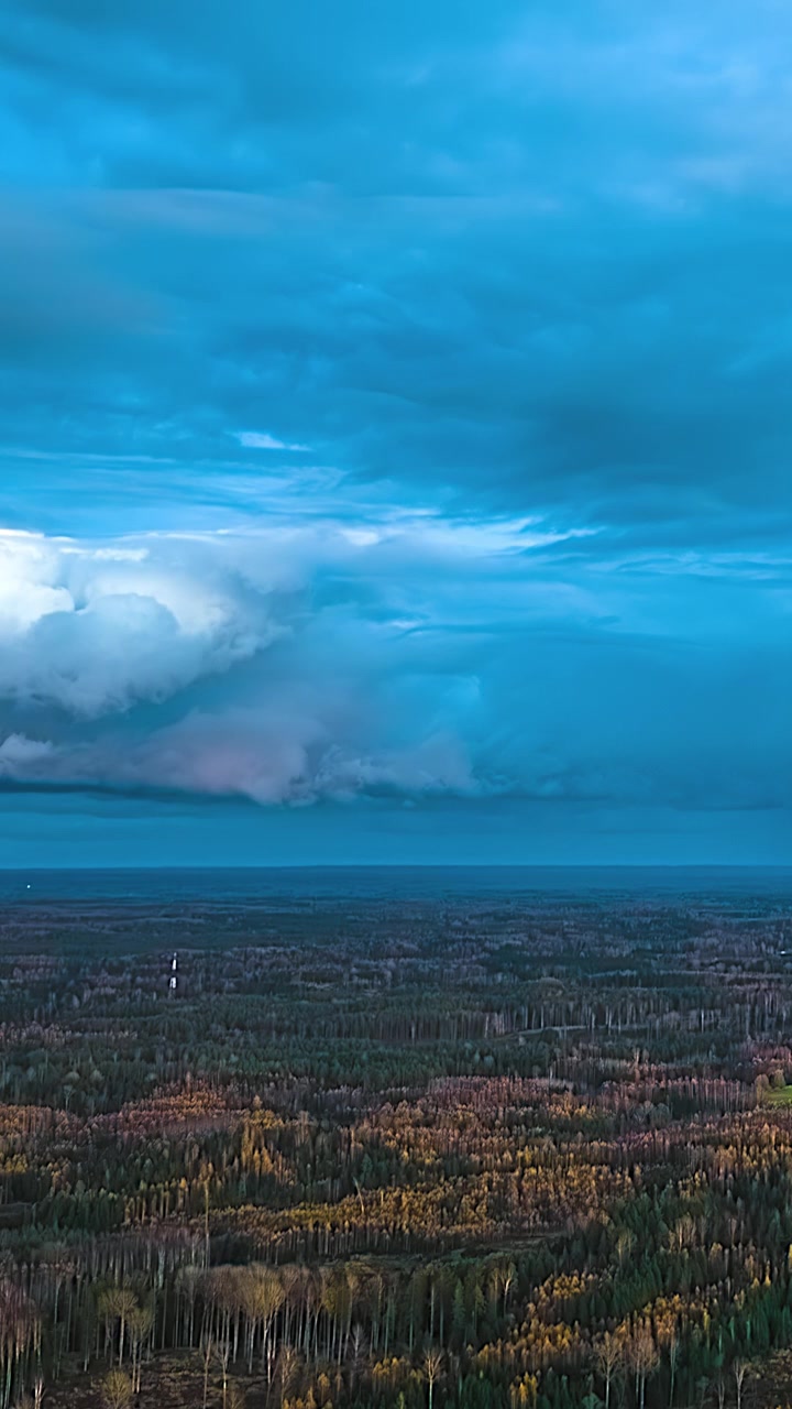 Tummat myrskypilvet ja kaukaiset sadealueet liikkuvat laajan metsäerämaan yli dramaattisen ilmakehän taivaan alla ylhäältä katsottuna.
