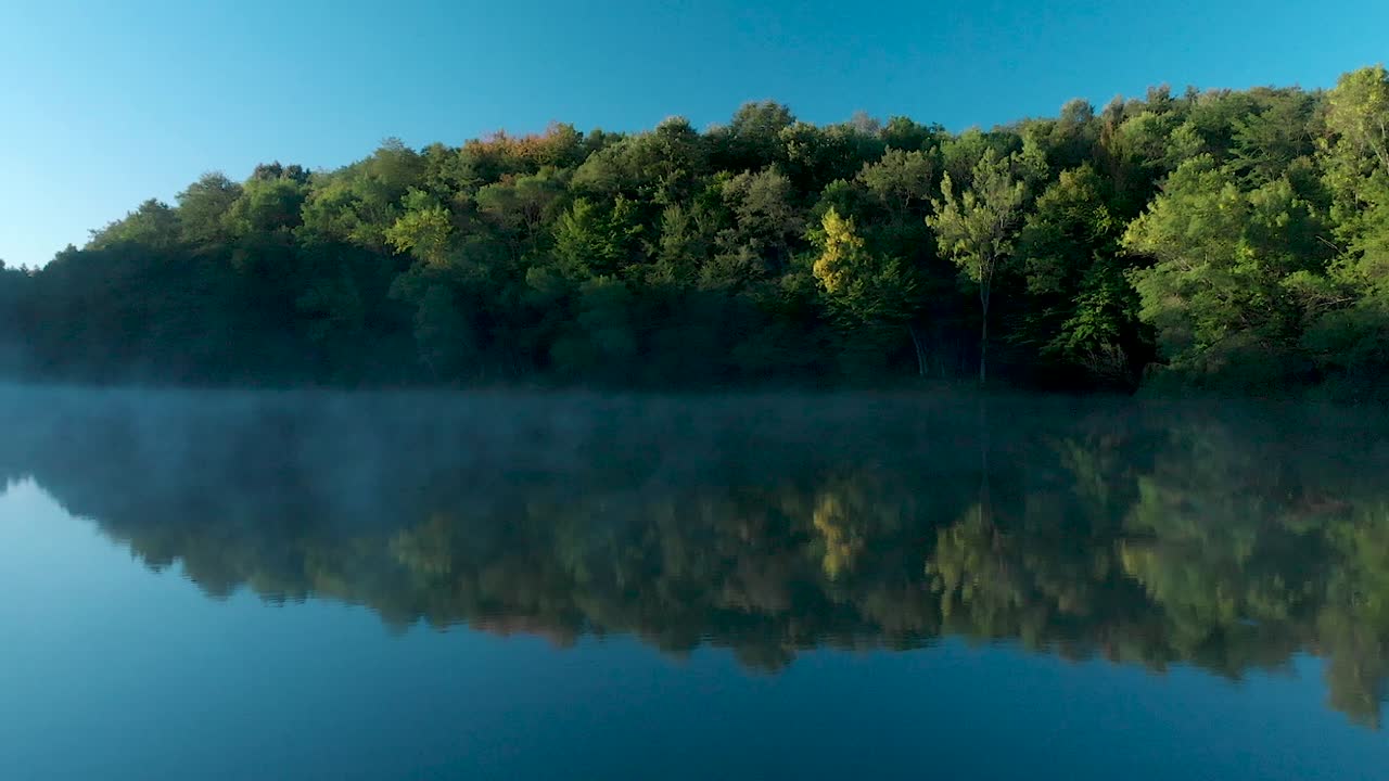 tiro panorámico temprano en la mañana sobre el lago brillante con algo de niebla