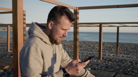 man using phone at the beach