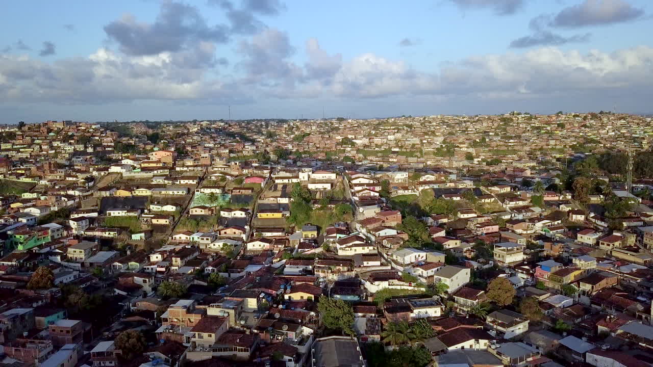 Daytime aerial footage over Macaxeira community in Recife Pernambuco Brazil showing hillside simple homes cars and precarious tarps depicting poverty danger and stark inequality in an urban area.