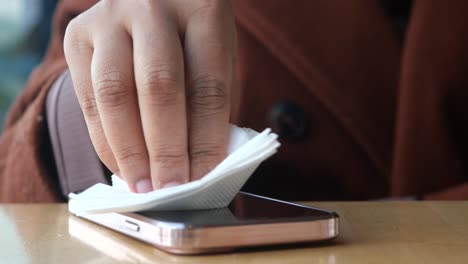 person cleaning their phone screen with a tissue