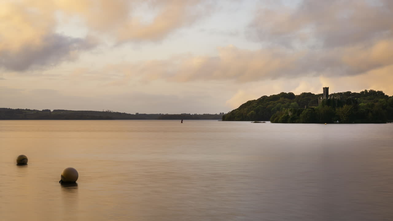 Time-lapse di una rovina di castello sull'orizzonte del lago durante un tramonto serale in Irlanda