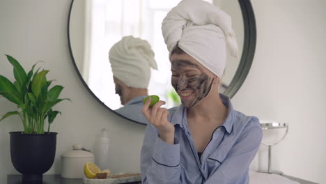 mujer con máscara facial y un limón mirando a la cámara