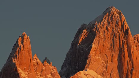 the jagged peaks of mount fitz roy are bathed in golden sunlight against a clear sky