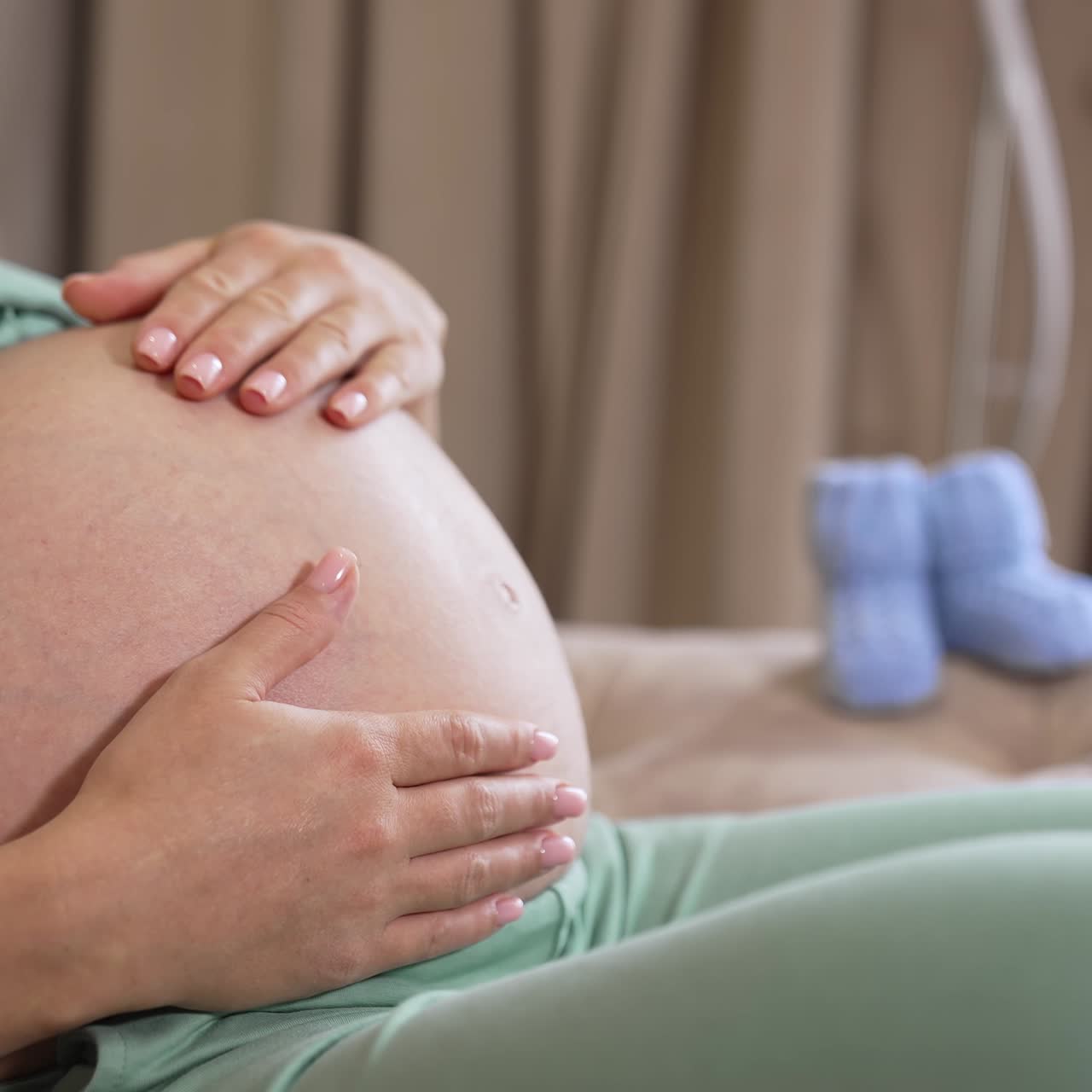 Donna incinta accarezza il pancione. Primo piano di donna incinta felice con il pancione a casa.
