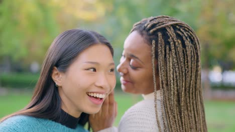 two friends sharing a secret and laughing outdoors