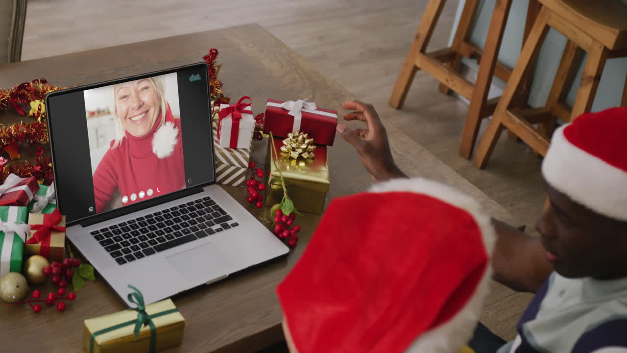 pareja diversa con sombreros de santa teniendo llamada de video portátil con mujer caucásica