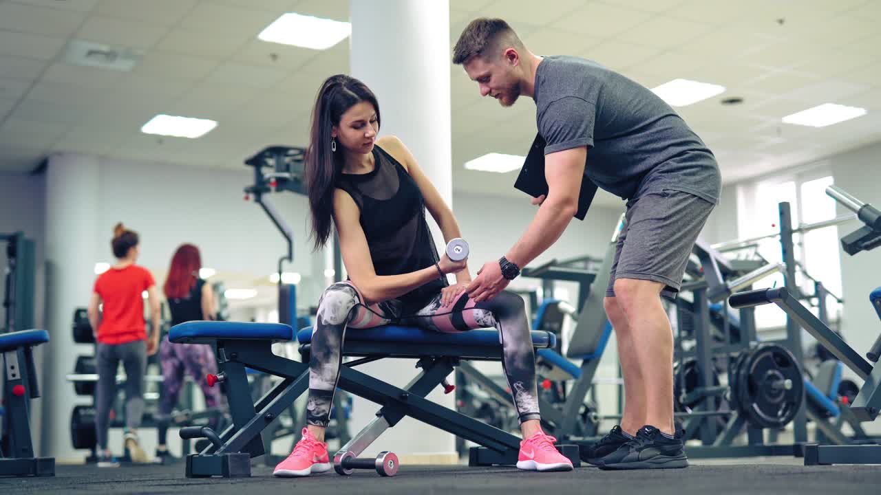 Young and beautiful woman working out with dumbbells in gym. Concept of a healthy lifestyle.