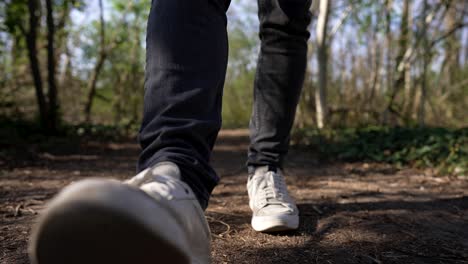 close up of foot with white shoes, walk on hiking trail in forest, slow motion