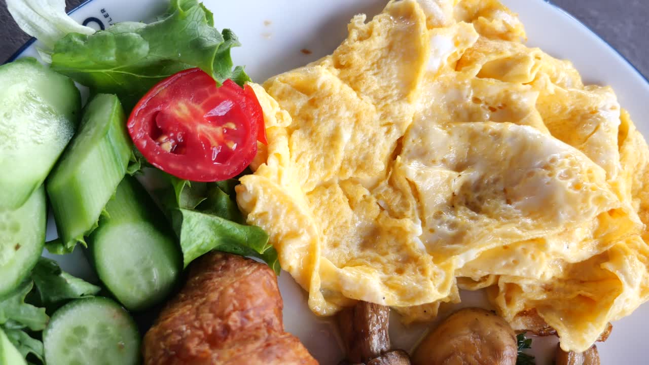Delicious Breakfast with Scrambled Eggs, Salad, and Croissant