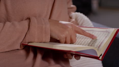 close up of muslim woman sitting on sofa at home reading or studying the quran 6