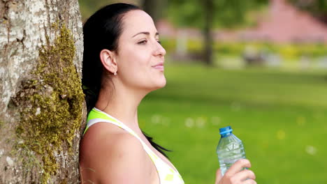 una bonita morena bebiendo de una botella de agua