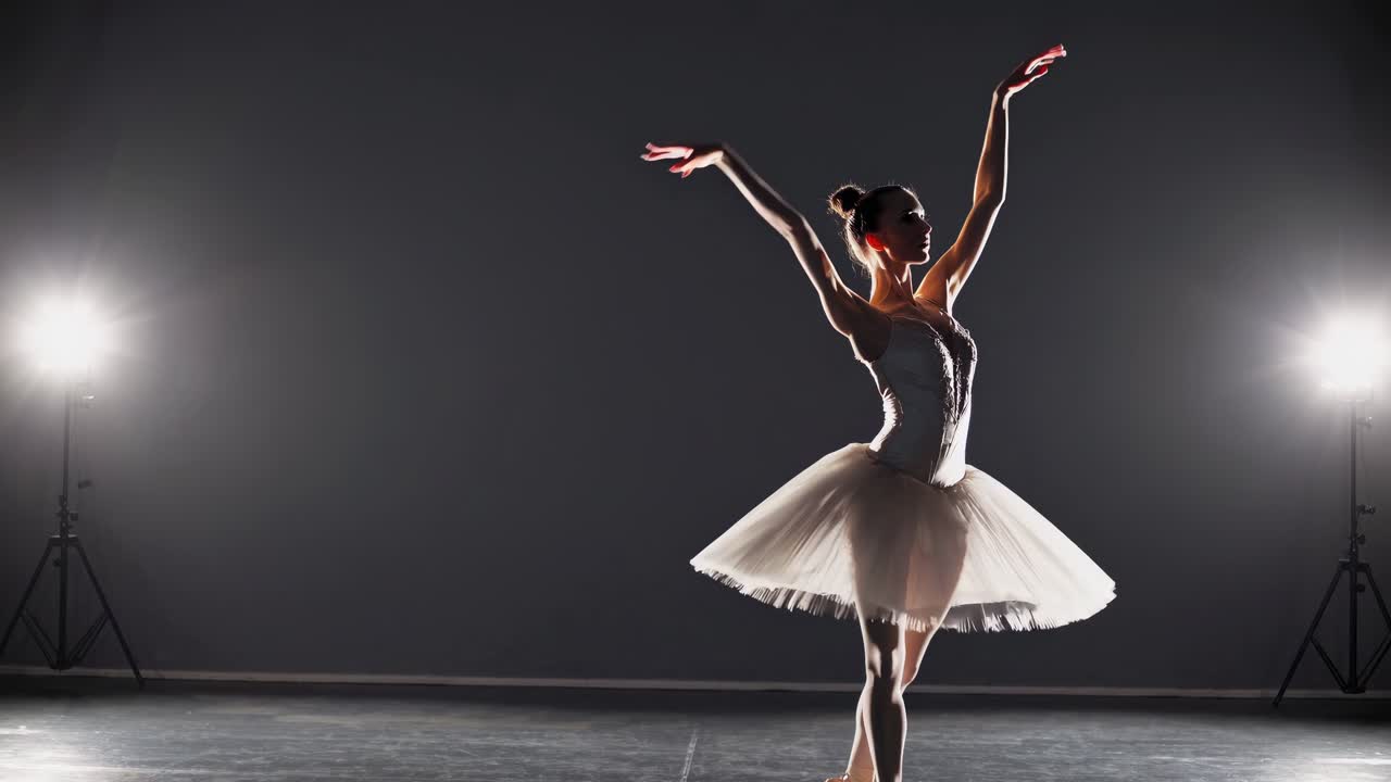 Uma imagem de vídeo dramática de uma bailarina de tutu, capturada de um ângulo baixo, com holofotes.