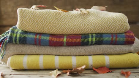 video of folded blankets and autumn leaves on wooden background