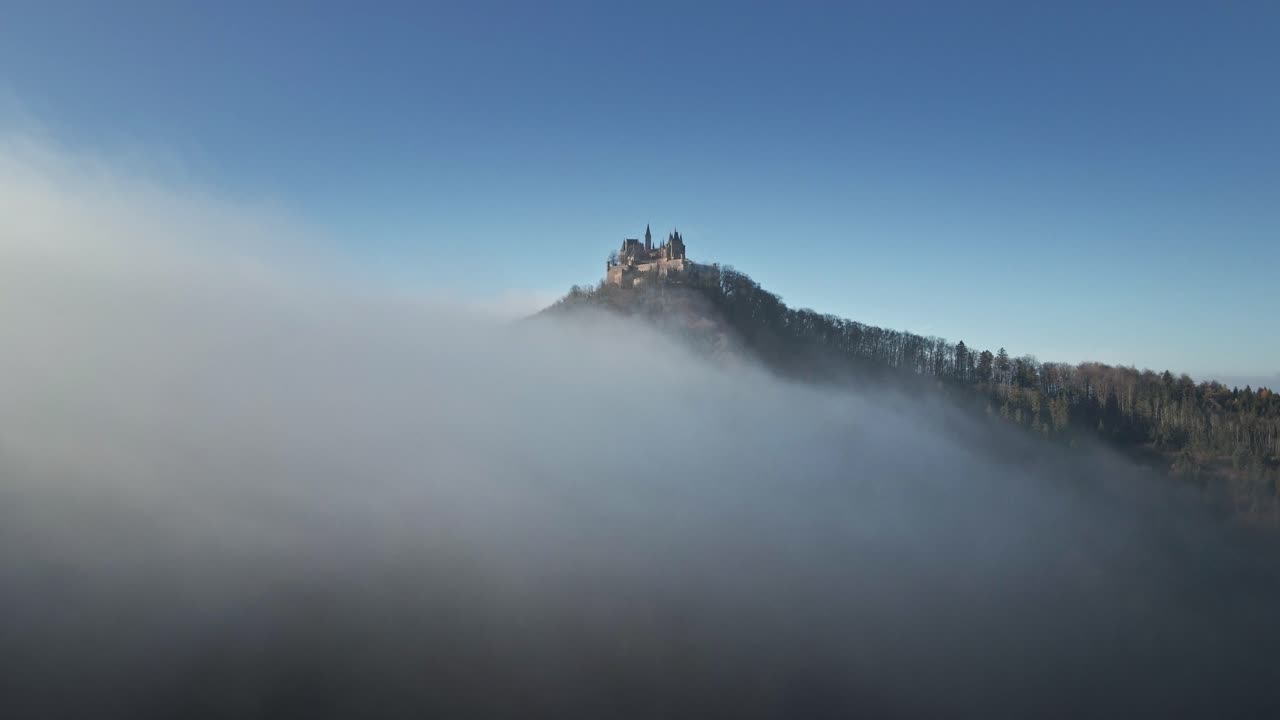 The drone continues its journey, moving further into the misty clouds above Hohenzollern Castle, blending the breathtaking German countryside with a mysterious, dreamlike atmosphere.