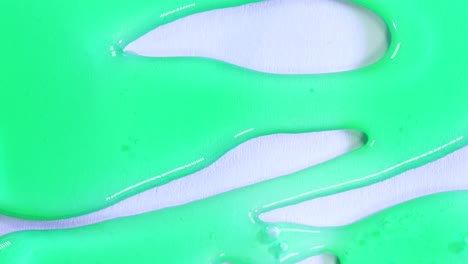 Green-translucid-dense-substance-falling-in-white-surface-background