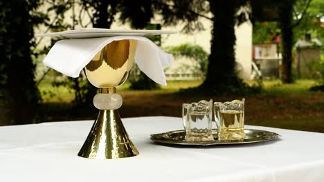 cáliz dorado junto con agua y vino sobre una mesa, preparado para un servicio