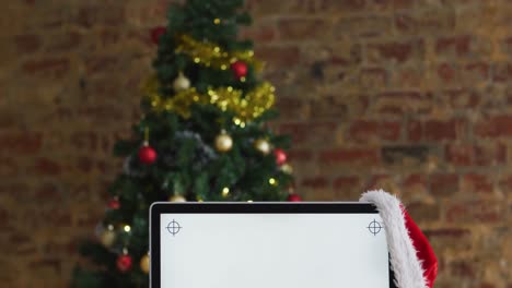 Video-of-computer-with-santa-hat-over-christmas-tree