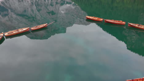 Aerial-shot-from-drone-over-aligned-boats-in-Braies-lake-in-the-Dolomites,-Italy