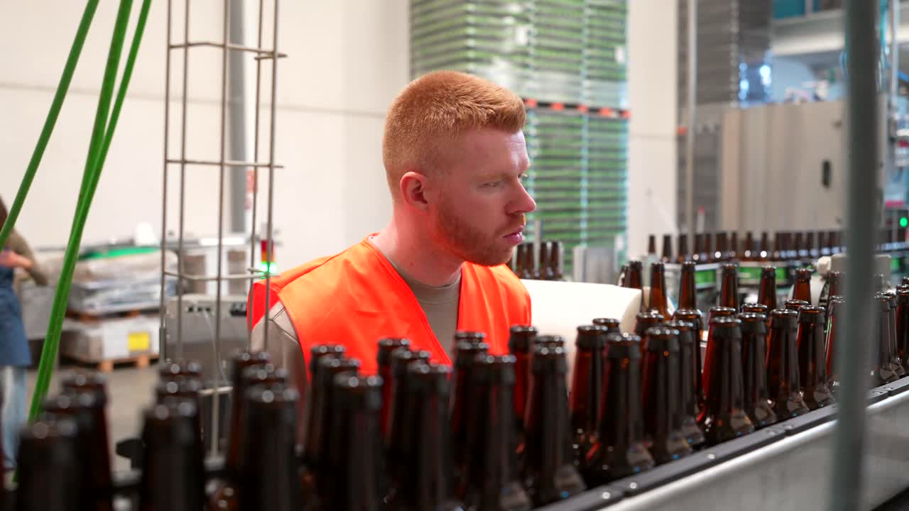 Man Inspecting Beer Bottles on a Production Line