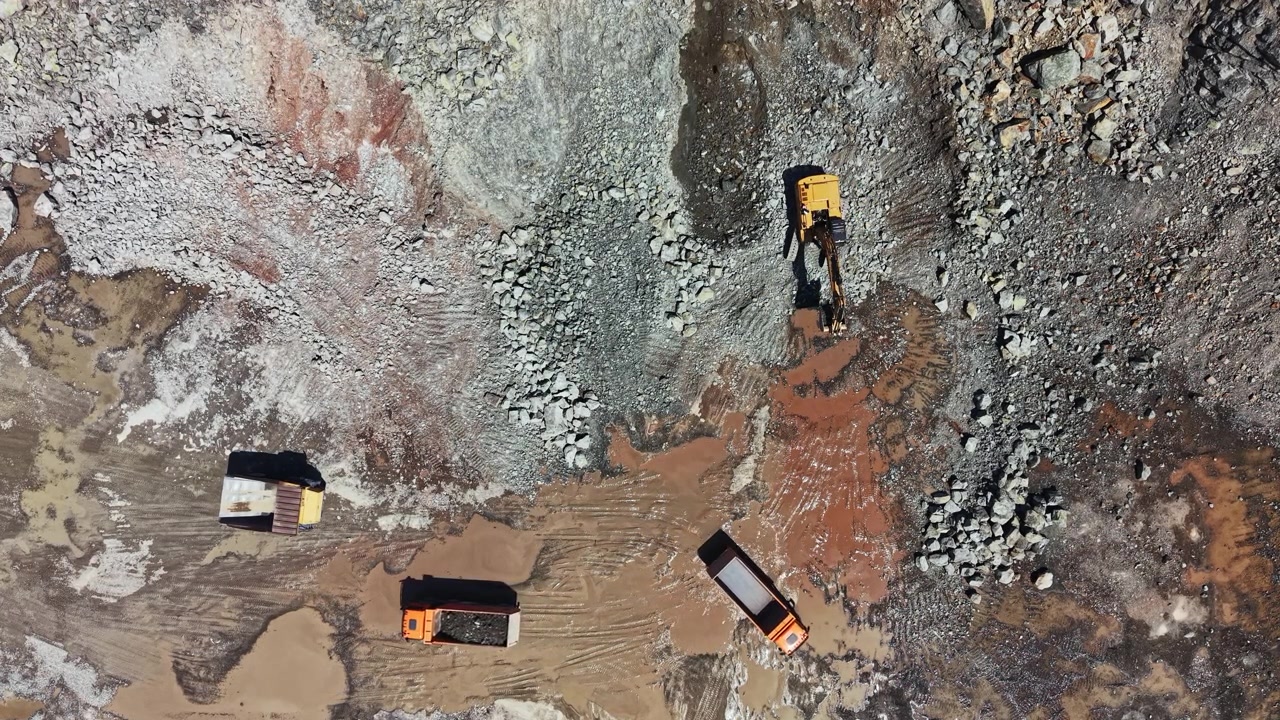 Granite quarry shows trucks and machinery working on site during daytime hours in a busy mining area