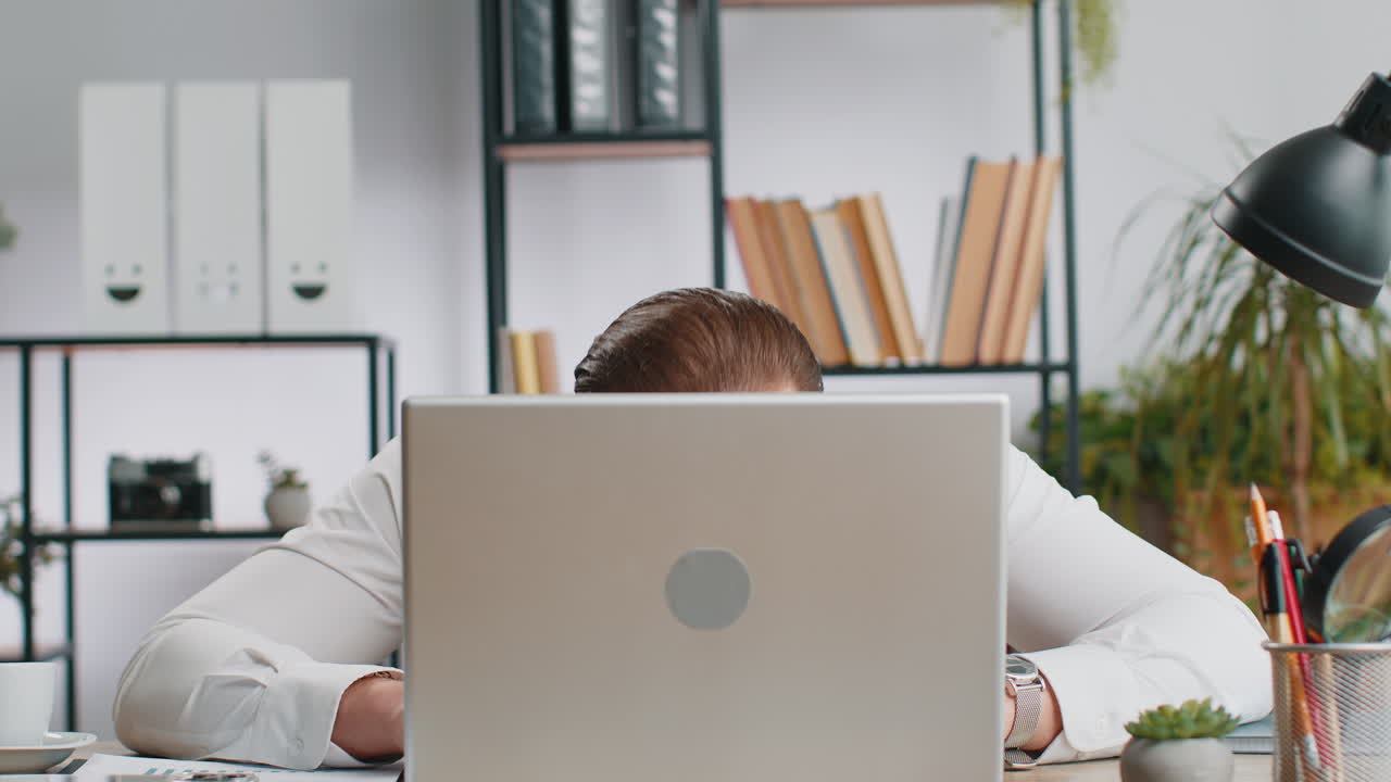 Office businessman hiding behind laptop computer making funny silly face fooling around disrespect