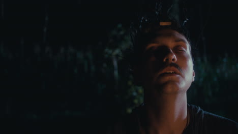 man with branch headpiece in dark forest at night