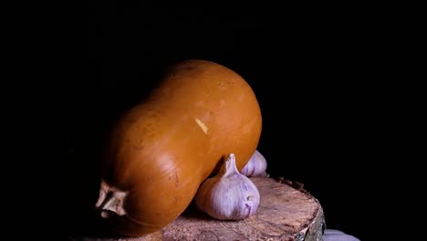 the pumpkin is orange and the head of garlic is spinning in the dark. pumpkin vegetable. head of garlic. spicy food. vegetarian food. agricultural harvest. home kitchen. halloween. video.