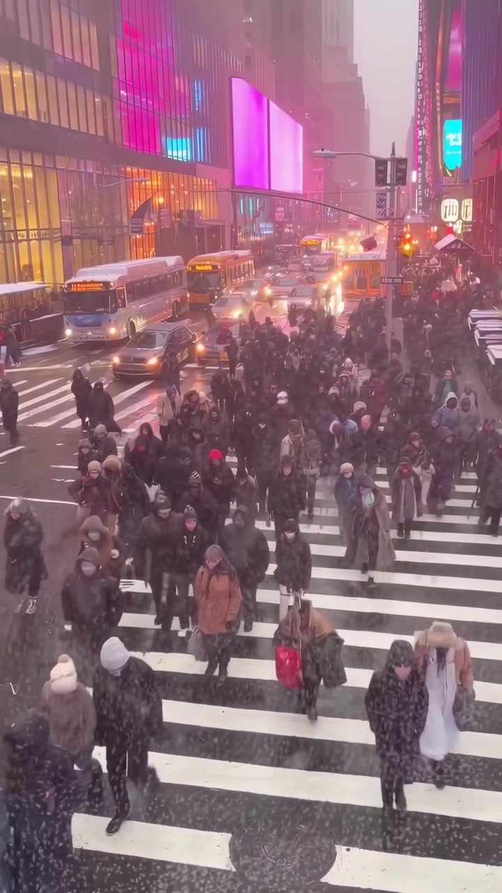Multidão de pessoas atravessando o cruzamento da Times Square durante nevasca
