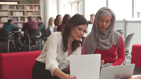 estudiante universitaria que trabaja en la biblioteca con un tutor