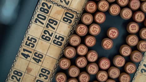 cinematic close-up smooth shot from above of a pile of bingo wooden barrels in a square, woody figures, old numbers background, vintage board game, slow motion 120 fps commercial rotating gimbal video