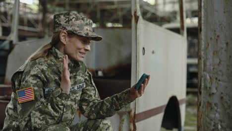 Woman Soldier in Camouflage Talking on Smartphone in Abandoned Industrial Building