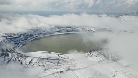 vista aérea de drones estáticos ram del lago cubierto de nieve con nubes gruesas de bajo nivel, israel
